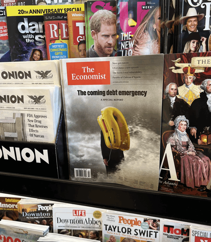 A magazine rack featuring 'The Economist' with a cover titled 'The coming debt emergency,' showing a person holding a yellow life preserver. Surrounding magazines include entertainment and lifestyle titles, conveying a mix of serious and lighthearted themes.